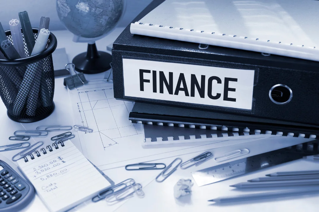 A picture consisting paper, scale, pencils and other finance related things with title finance